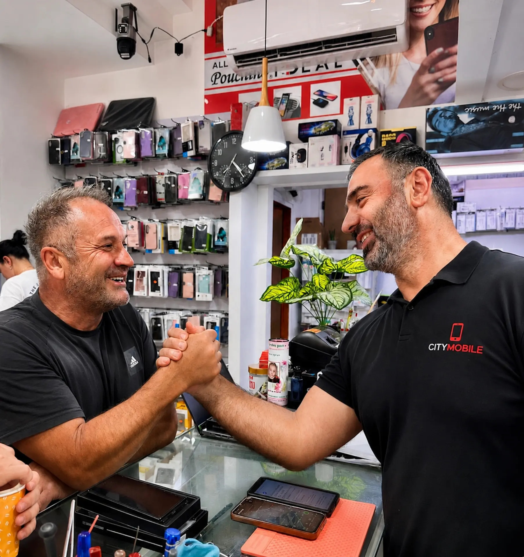 מיכאל, בעל החנות, לוחץ יד ללקוח בתוך החנות CityMobile